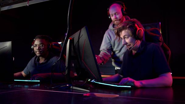 Durante o torneio de estratégia, dois caras da equipe jogam nos computadores, o treinador observa por trás e jura: - Foto, Imagem
