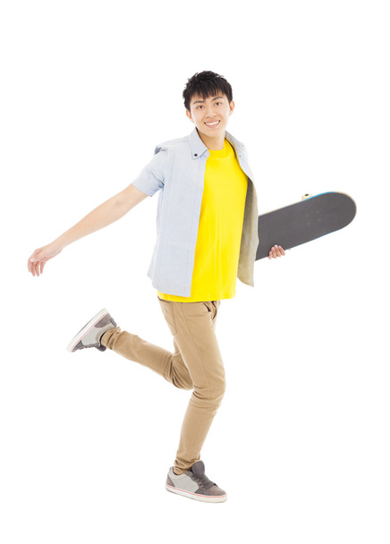 Vibrant young man holding a skateboard and walking  - Fotografie, Obrázek