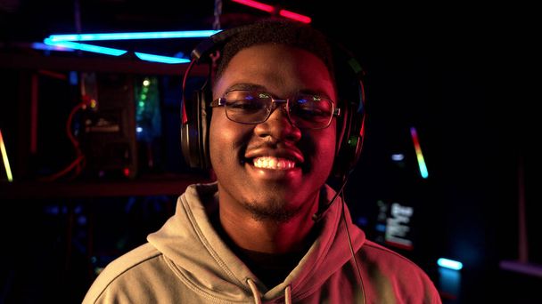 Detailní portrét roztomilého černého studenta v brýlích a sluchátkách, usmívající se do kamery - Fotografie, Obrázek