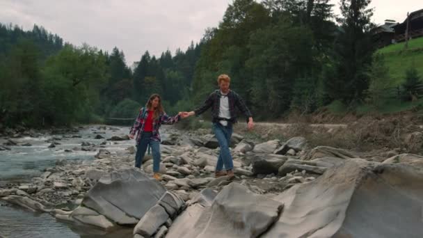 Paar wandert entlang des Gebirgsflusses. Reisende gehen am felsigen Ufer des Flusses - Filmmaterial, Video