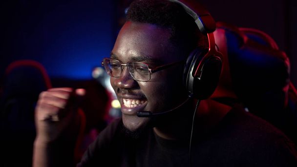 Afrykański facet w słuchawkach i okularach prowadzi internetowy strumień podczas mistrzostw gier komputerowych - Zdjęcie, obraz
