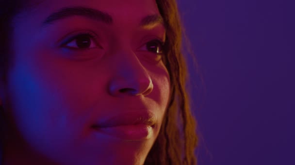 Közel portré komoly fiatal afro-amerikai nő néz félre, pózol neon fények, szabad tér - Felvétel, videó