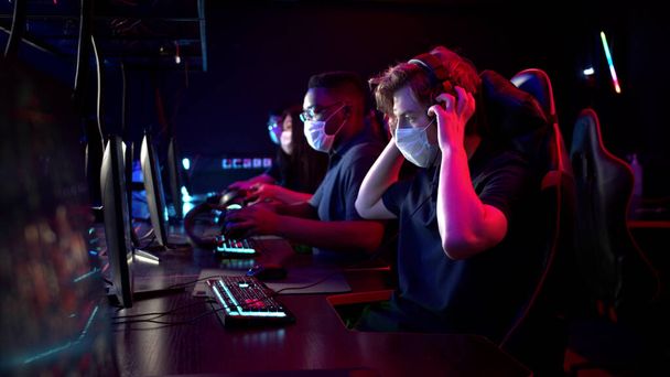 Білошкірі та чорношкірі хлопці є членами команди онлайн стратегій кіберспорту. Грати за комп'ютером на міжнародному турнірі під час пандемії
. - Фото, зображення