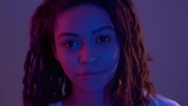 Použij svou mysl. Studio portrét mladé africké americké ženy ukazující na její hlavu v neonových světlech - Záběry, video