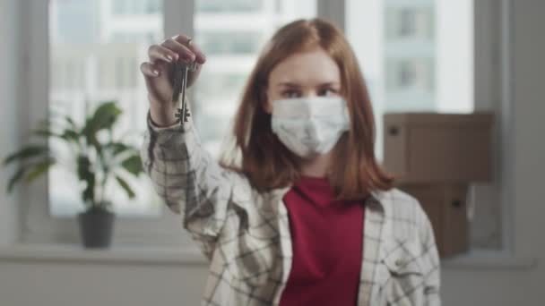 Γυναίκα με ιατρική μάσκα κουνάει τα πλήκτρα μπροστά από την κάμερα - Πλάνα, βίντεο