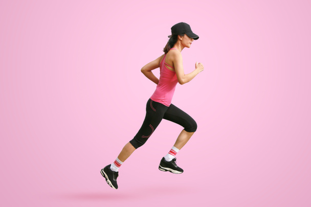 Deportiva corredora en silueta sobre fondo rosa. Vista lateral. Deporte y estilo de vida saludable - Foto, Imagen