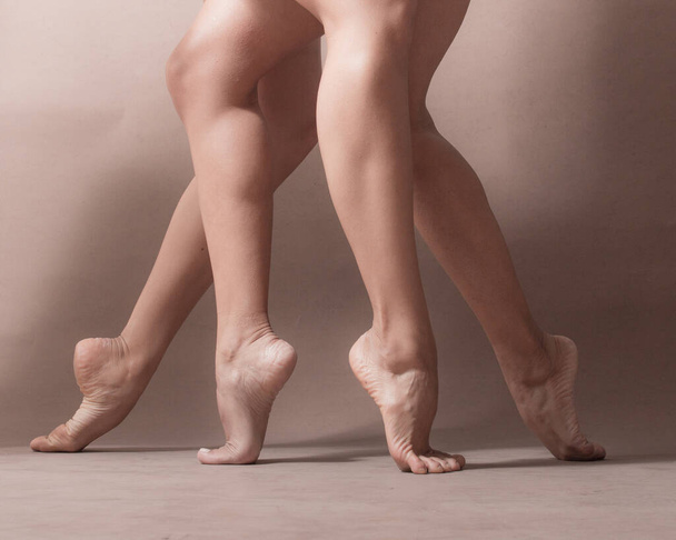 Piernas de dos bailarinas latinas artistas de pie de puntillas con sus pies desnudos - Foto, Imagen