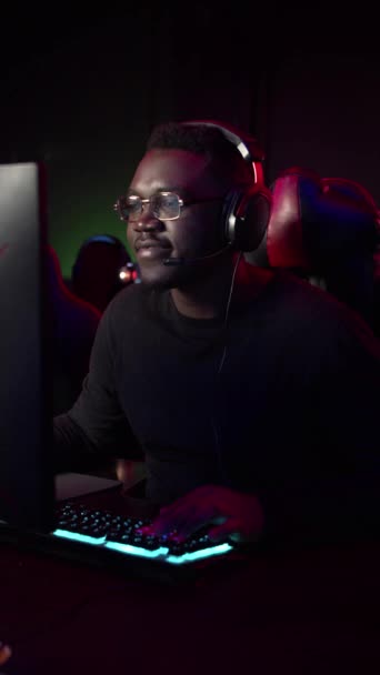 Un tipo dalla pelle scura gioca a un videogioco al computer, parla con i suoi compagni di squadra parlando in squadra - Filmati, video