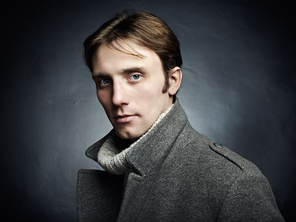 Artistic dark portrait of the young beautiful man in a gray coat - Фото, зображення