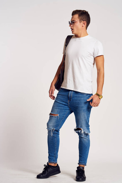 mężczyzna z plecakiem na plecach w dżinsach T-shirt pełnej długości tenisówki i okulary na twarzy - Zdjęcie, obraz