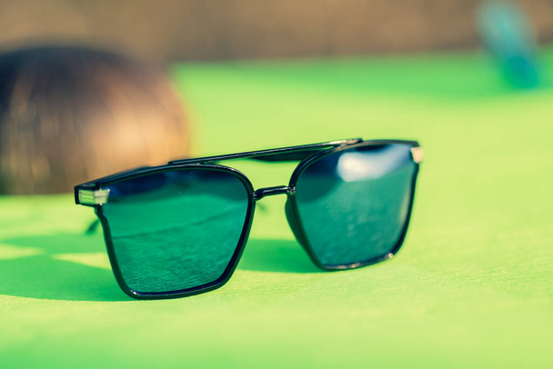 Модель негабаритних сонцезахисних окулярів з великими блакитними лінзами знімається на вулиці в літній день крупним планом. Вибірковий фокус
 - Фото, зображення