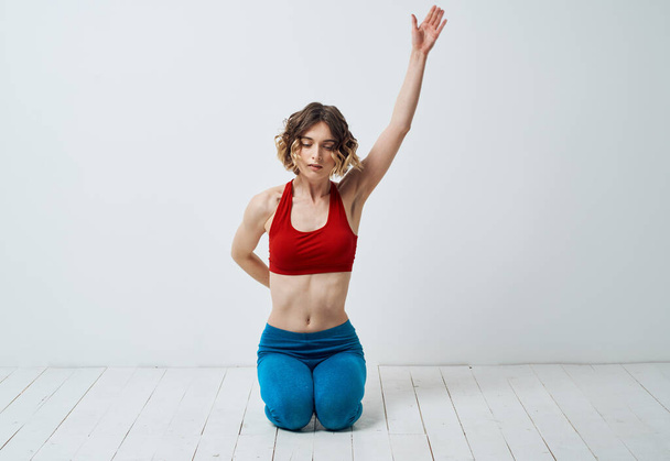 Mujer en ropa deportiva sobre un fondo ligero gestos con sus manos yoga asana - Foto, Imagen