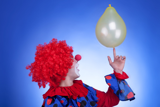 Clown in red costume playing with yellow ballon - Photo, Image