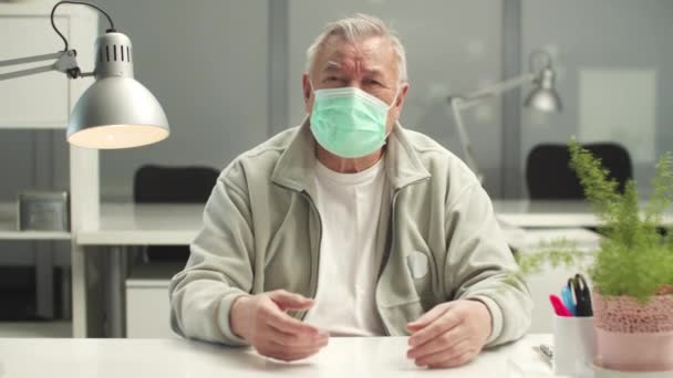 Een volwassen man is blij om het medische masker af te doen en de plant te ruiken, hij voelt de geuren en is er blij mee - Video