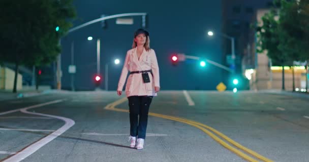Κομψή γυναίκα με μοντέρνα φουτουριστικά κοσμικά ρούχα που περπατά δίπλα σε άδεια νυχτερινή πόλη 4K - Πλάνα, βίντεο