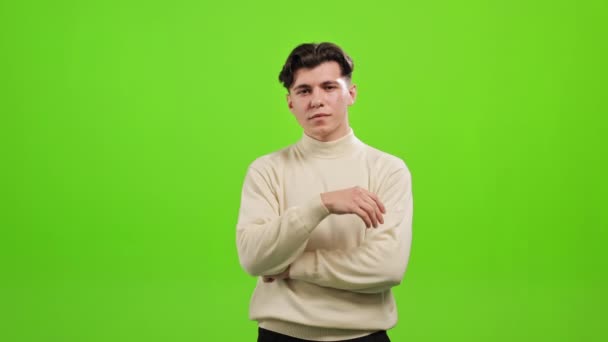 The man is standing and looking at the camera. He is raising his hand to his chin and thinking. He is standing on a green background. Green screen. 4K - Footage, Video