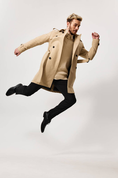 man in a beige coat circle movement light background - Фото, изображение