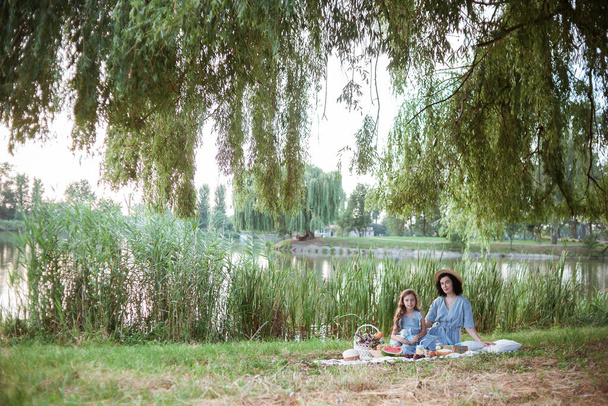 Μητέρα και κόρη σε πικνίκ σε πάρκο στις όχθες ενός ποταμού. - Φωτογραφία, εικόνα