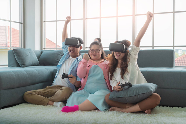 Asian Family with Down Syndrome kid is playing VR glasses Gra na podłodze ze zwycięskim wyrażeniem. - Zdjęcie, obraz