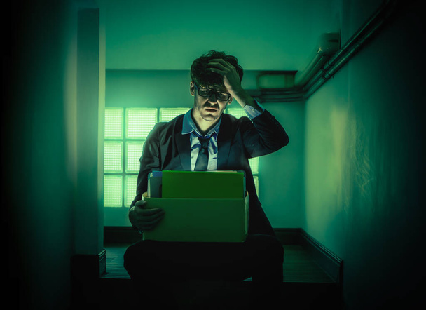 Deprimido Umemployed Trabalhador de escritório de negócios está sentado com caixa de cartão na escadaria escura estreita para ser demitido conceito. - Foto, Imagem