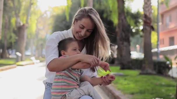 彼らが屋外に歩いている間、幸せな母親は彼女の息子と遊ぶ。身体障害のある子供。屋外で幸せな愛の家族を楽しむビデオ。幸せな瞬間だ。障害者介護の概念 - 映像、動画