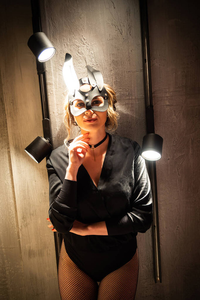 BDSM tavşan derisi maske ve aksesuarlı siyah iç çamaşırlı seksi kadın. Işıkların arka planında poz vermek. - Fotoğraf, Görsel