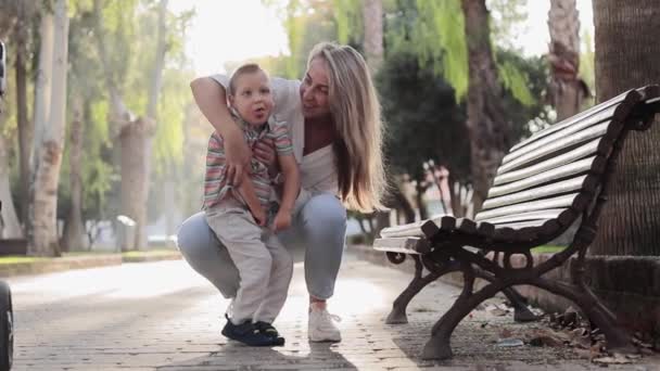 Szczęśliwa mama bawić się z synem podczas spaceru na zewnątrz. Dzieciak z niepełnosprawnością fizyczną. Film z cieszyć się szczęśliwą rodziną miłości na świeżym powietrzu. Szczęśliwe chwile. Koncepcja opieki nad niepełnosprawnymi - Materiał filmowy, wideo