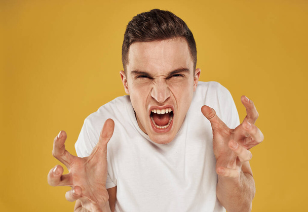 Man in a white T-shirt on a yellow background portrait close-up model cropped view gesturing with hands - Foto, Imagen