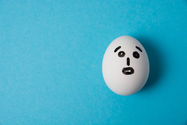 Яйцо с удивленным лицом. Изолировать на синем фоне - Фото, изображение