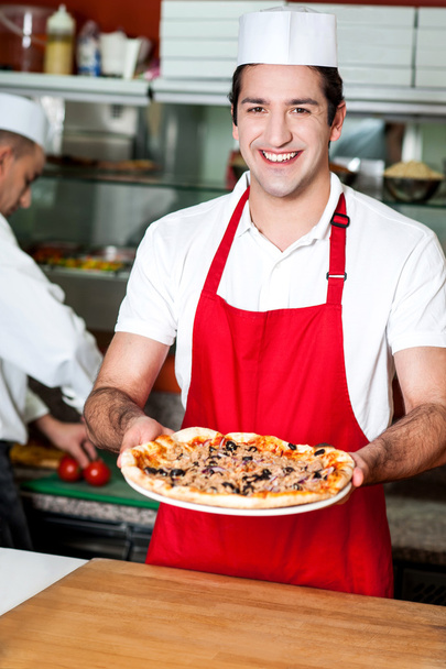 Sorrindo jovem chef masculino entregando pizza
 - Foto, Imagem