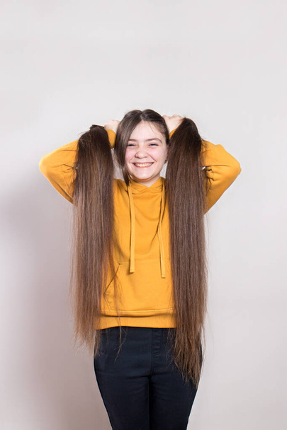Une adolescente de 12 ans aux cheveux naturels très longs sourit. Photo verticale avec une place pour l'espace de copie de texte. Coiffeur pour enfants, coupe de cheveux, coiffures pour les cheveux longs chez les enfants. - Photo, image