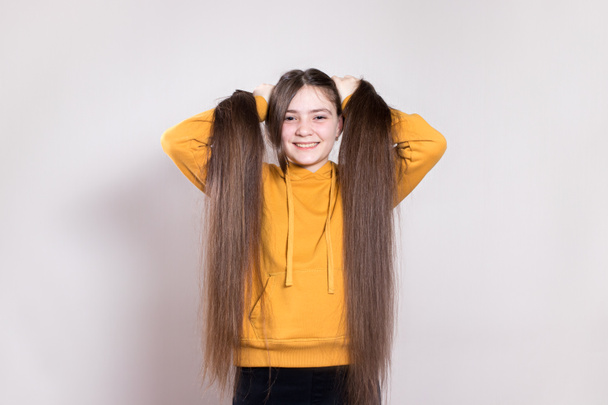 A 12-year-old teenage girl with very long natural hair smiles. Horizontal banner with a place for text copy space. Children's hairdresser, haircut, hairstyles for long hair in children. - Photo, Image