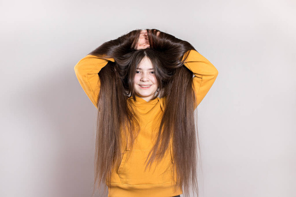 Egy 12 éves tinédzser lány nagyon hosszú természetes hajmosollyal. Vízszintes transzparens szövegmásolási hellyel. Gyermek fodrász, frizura, frizura a hosszú haj a gyermekek számára. - Fotó, kép