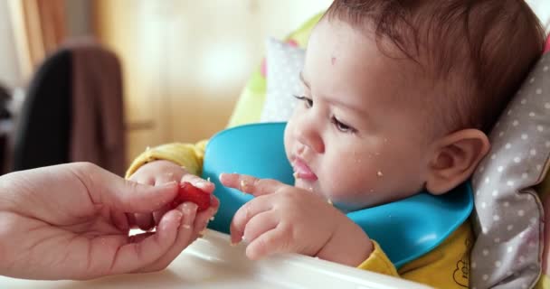 Äiti pitää vauvaa sylissään ja ruokkii poikaansa lusikalla. perhe, ruoka, lapsi, syöminen ja vanhemmuus käsite - Materiaali, video