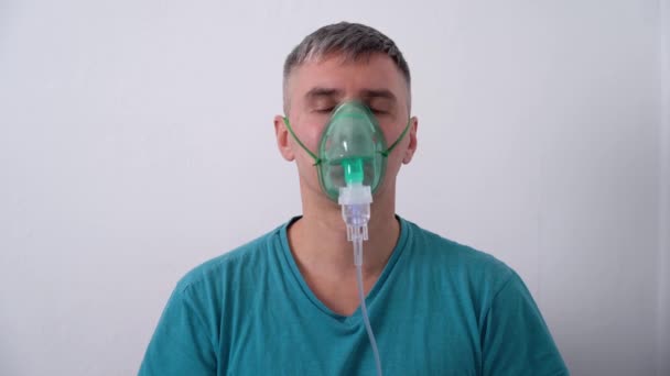 Mann kämpft mit dem Atem, während er eine Sauerstoffmaske trägt und sich selbst von der COVID-19 Pandemie isoliert. - Filmmaterial, Video