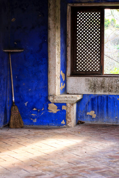 Εγκαταλελειμμένη σκούπα και πολύχρωμη υφή σε έναν παλιό μπλε βαμμένο τοίχο - Φωτογραφία, εικόνα