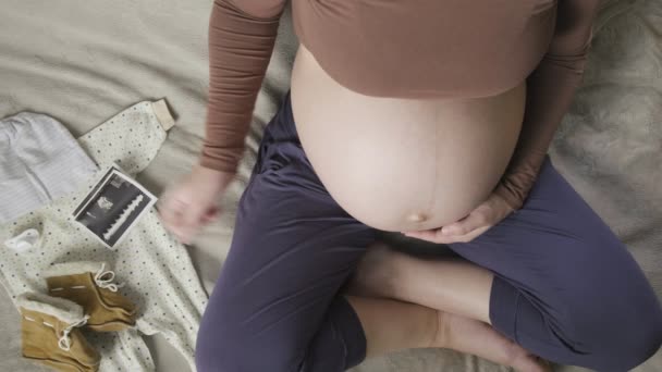 Top vew de mujer embarazada embarazada embarazada con el vientre grande mirando ecografía - Metraje, vídeo