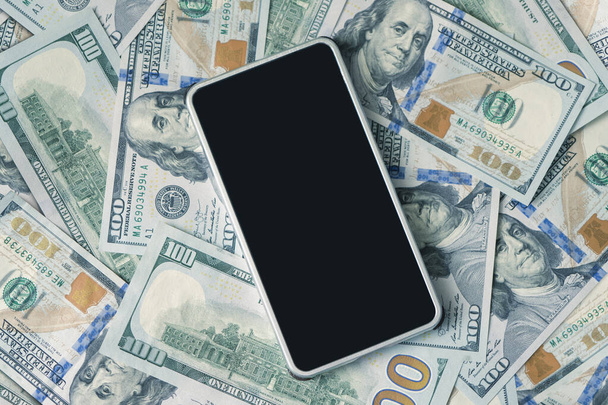 Dollar bills and smartphone, copy space, top view. blank black smartphone screen for text and design. the concept of accumulating profitability and earnings through a smartphone. - Photo, Image