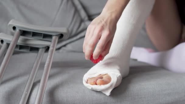 μια γυναίκα ζεσταίνει τα μουδιασμένα δάχτυλα των ποδιών στο γύψο - Πλάνα, βίντεο