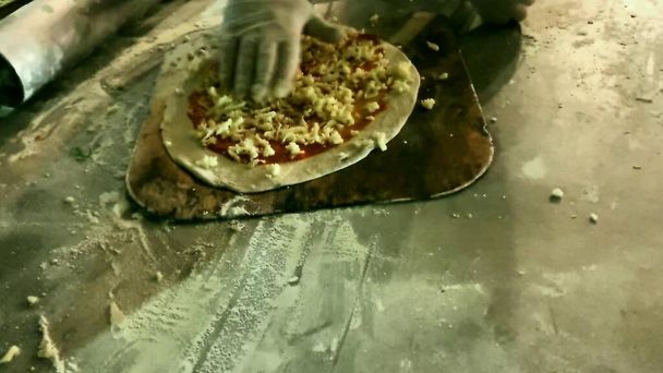 El proceso de hacer pizza de masa, salsa de tomate y queso. Aplicar salsa de tomate y queso rallado sobre la masa laminada. Movimiento lento. - Foto, imagen