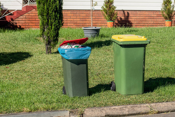 Αυστραλιανοί κάδοι σκουπιδιών με πολύχρωμα καπάκια για γενική και ανακύκλωση οικιακών απορριμμάτων στο πεζοδρόμιο μετά τη συλλογή απορριμμάτων του συμβουλίου - Φωτογραφία, εικόνα