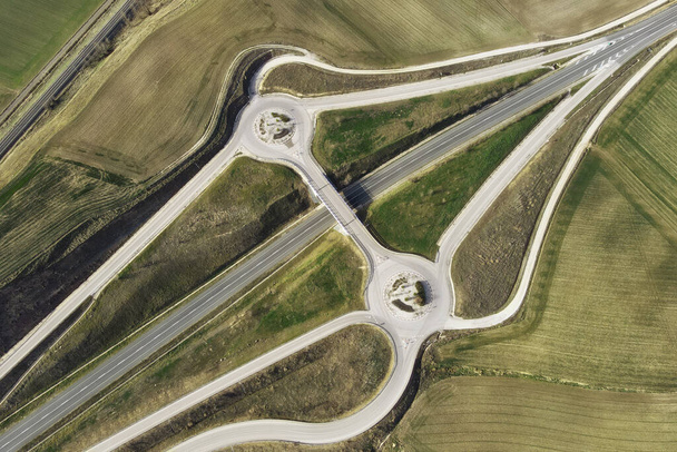 Vista aérea de un avión no tripulado sobre una intersección de carreteras rurales. Tráfico en sobrevuelo en el paisaje rural - Foto, Imagen