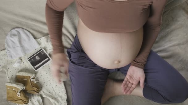 mulher grávida sentada na cama, derramando pílulas de garrafa na palma da mão, vista superior - Filmagem, Vídeo