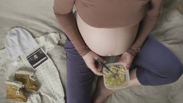 Top vew of expecting pregnant woman with large belly eating pasta at home - Footage, Video