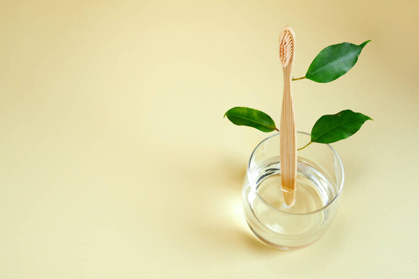 Wooden bamboo toothbrush with leaves on glass. Zero waste, Eco-friendly concept. - Fotografie, Obrázek