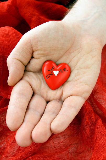 A férfi kezében egy piros háttér piros szív - Fotó, kép