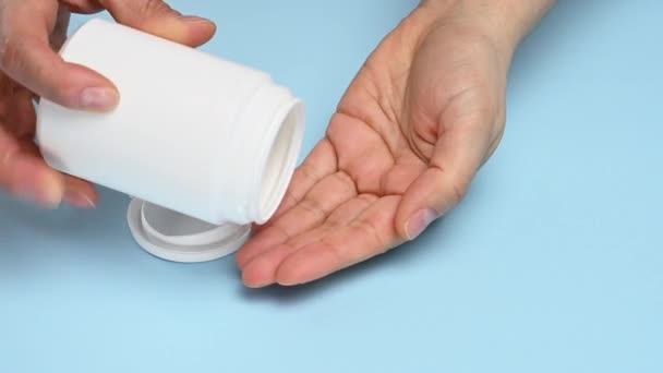 valkoiset pyöreät pillerit putoavat naisen käteen valkoisesta muovipurkista, sairauksien hoidosta, huumeriippuvuudesta - Materiaali, video