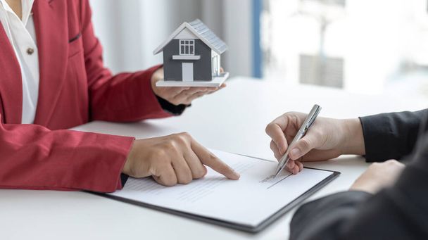 Υπογράφοντας μια σύμβαση αγοράς σπιτιού, διευθυντής πωλήσεων έχει προτείνει όρους και προϋποθέσεις για τους πελάτες που υπογράφουν συμφωνίες αγοράς σπιτιού με την ασφάλιση, συμφωνία για την υπογραφή της έννοιας της σύμβασης αγοράς. - Φωτογραφία, εικόνα