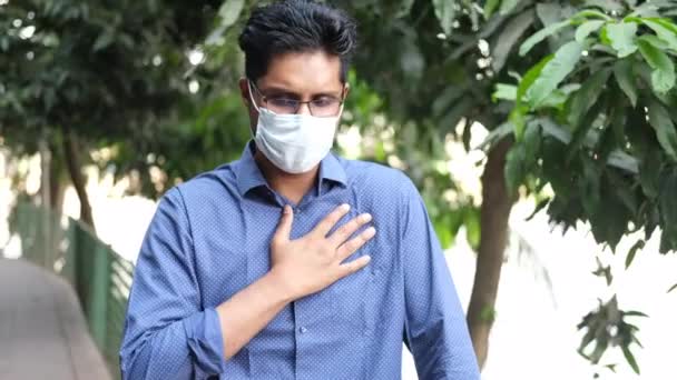  молодой азиат в маске для лица кашляет и чихает на открытом воздухе  - Кадры, видео
