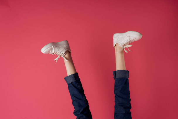 White sneakers upside down legs movement street fashion pink background - Foto, Bild